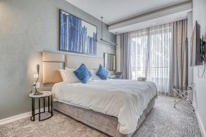 sypialnia z dużym łóżkiem z niebieskimi poduszkami w obiekcie The Capital in Sandton w mieście Johannesburg