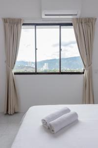 a white bed with two towels on it in front of a window at The Eastern, by Meixi in Jelutong