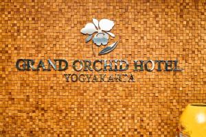ein Schild an der Seite eines Gebäudes mit einer Blume in der Unterkunft Grand Orchid Hotel Yogyakarta in Yogyakarta