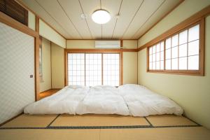 uma cama grande num quarto com duas janelas em Biwako Galaxy em Katsuno