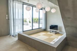 uma sala de estar com televisão e janelas grandes em Nashiro White Cube - Vacation STAY 14460 em Itoman