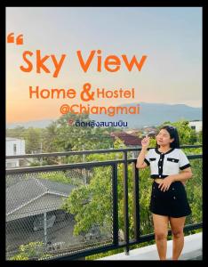清邁的住宿－Sky View Home and Hostel Chiangmai，站在阳台上喝一杯酒的女人