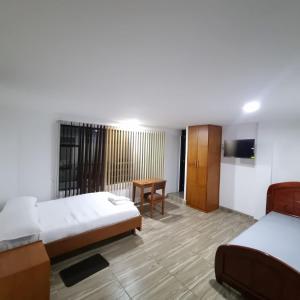 a hotel room with two beds and a desk at Hotel San Marcos Las Lajas in Ipiales