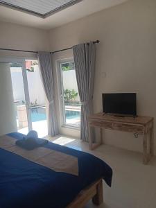 een slaapkamer met een bed, een tv en ramen bij Hasta La Vista Villa Amed in Amed