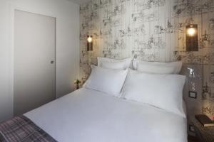 a white bed with white pillows in a bedroom at Le Mireille in Paris