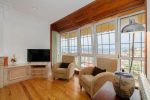sala de estar con sillas, TV y ventanas en La Casa De Rita, en Baiona