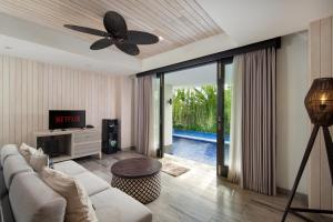 ein Wohnzimmer mit einem Sofa und einem Deckenventilator in der Unterkunft AmantraNa Canggu in Canggu