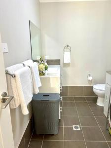 a bathroom with a sink and a toilet and towels at Guest house in Harrington Park in Narellan