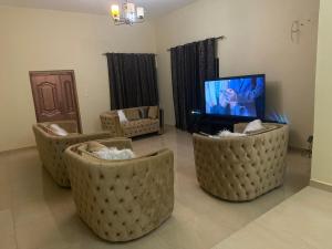 a living room with three couches and a tv at Prestigious Elegant Duplex - Abasscee in Freetown