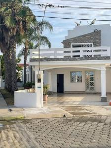 un grand bâtiment blanc avec un palmier en face dans l'établissement Casa del Mar Malin, à Ballenita