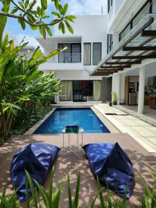 a swimming pool with two blue chairs next to a house at Jadin Villa at Nusa Dua Bali in Nusa Dua