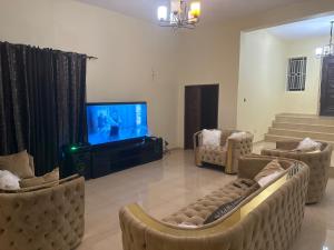 a living room with couches and a flat screen tv at Prestigious Elegant Duplex - Abasscee in Freetown