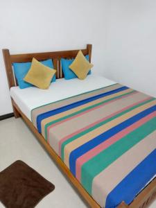 a bed with colorful striped sheets and pillows at River Paradise in Kalutara