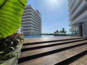 a boardwalk leading to a swimming pool with two buildings at Sea View Apartment at Nuvasa Bay Kalani Tower in Nongsa Area in Telukmataikan