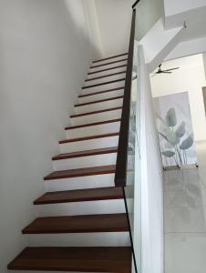 una escalera en una casa con paredes blancas y suelo de madera en 18 My home, en Nusajaya