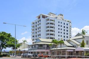 un gran edificio blanco con coches estacionados frente a él en An Adorable Apartment on Abbott - Stunning Views en Cairns