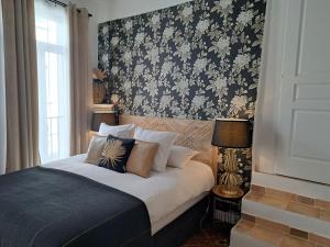 a bedroom with a bed with a floral wallpaper at Hôtel Le Patio de Sophie in Sisteron