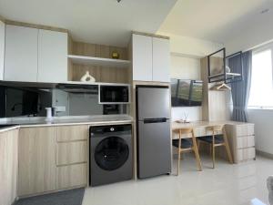 a kitchen with a washer and dryer next to a table at Sea View Apartment at Nuvasa Bay Kalani Tower in Nongsa Area in Telukmataikan