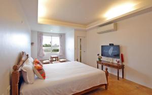 1 dormitorio con 1 cama grande y TV en Jin Zhu Ya Homestay, en Wujie