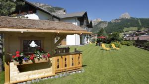 a gazebo with flowers in a yard next to a house at Residence Villa al Sole in Selva di Val Gardena