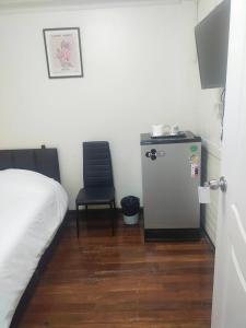 Zimmer mit einem Bett, einem Stuhl und einem Kühlschrank in der Unterkunft Orchid House in Bangkok