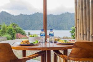 - une table avec deux assiettes de bouteilles d'eau et de nourriture dans l'établissement Cabana Bali Villa, à Kintamani