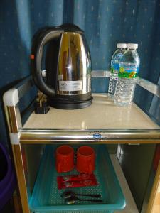 a coffee maker on a shelf with cups and water at D'pinggir Guest Room in Kuala Tahan