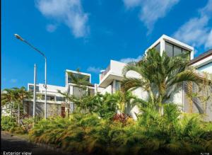 a building with palm trees in front of it at Jadin Villa at Nusa Dua Bali in Nusa Dua