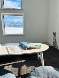 una mesa blanca con un libro delante de una ventana en Shooting Star the Bed & Breakfast, en Furano