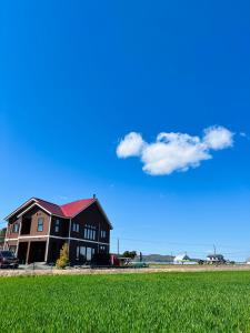 a black house with a red roof in a field at Shooting Star the Bed & Breakfast in Furano