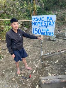 a man is standing next to a sign at Sue Pa Family Trekking Homestay in Sa Pả