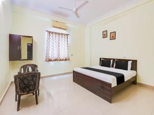 a bedroom with a bed and a chair in it at OYO Flagship HOTEL SS ELITE in Karīmnagar
