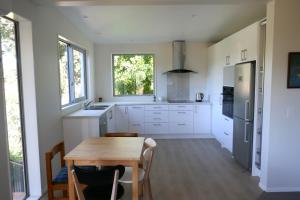 uma cozinha com armários brancos e uma mesa de madeira em The Tree house em Paraparaumu