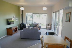 uma sala de estar com um sofá e uma mesa em The Tree house em Paraparaumu