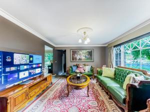 ein Wohnzimmer mit einem grünen Sofa und einem Flachbild-TV in der Unterkunft Pride Leisure Tudor House in Park Orchards