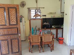 サンティ・ニケタンにあるARANYAK Homestayのテーブルと椅子、冷蔵庫のあるキッチン