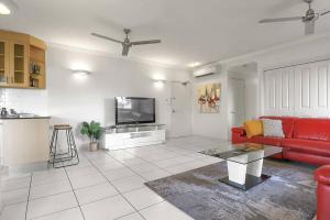 a living room with a red couch and a tv at An abode on Abbott - In the heart of the city in Cairns