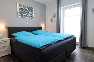 een slaapkamer met een bed met blauwe lakens en een raam bij ROBERTA - mit Terrasse und Sauna in Diemelsee