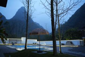 uma vista para uma piscina com um guarda-sol de palha em Yangshuo Vivian Villa em Yangshuo