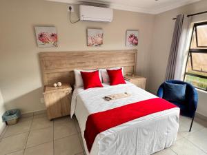 a bedroom with a large bed with red pillows at Numbigate Resort & Conference in Hazyview