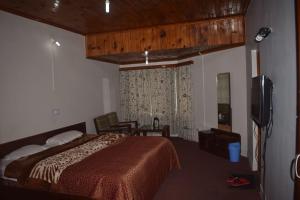1 dormitorio con 1 cama y TV en Heritage Aksa, en Pahalgām