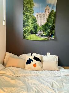 una cama con sábanas blancas y una pintura en la pared en 홍대 입구역 7min, Designer house, 대형빔, 2R, 포토존, 신축, 최대5인 en Seúl