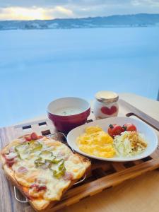 a table with a pizza and a plate of food at Shooting Star the Bed & Breakfast in Furano