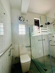 uma casa de banho com um WC e uma cabina de duche em vidro. em Casa Winnie em Kelaniya