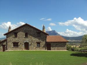 una casa in pietra su un campo con montagne sullo sfondo di Casa Rural O Fraginal a Guasillo