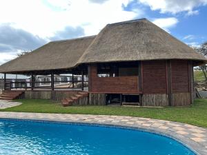 a building with a thatched roof next to a swimming pool at Numbigate Resort & Conference in Hazyview
