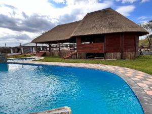 a resort with a thatched building and a swimming pool at Numbigate Resort & Conference in Hazyview