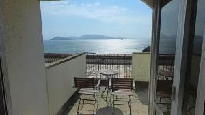 Un balcón con sillas y una mesa y el océano. en HOTEL GREEN PLAZA SHODOSHIMA - Vacation STAY 81149v, en Ikisue