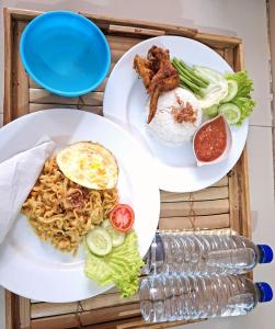 zwei weiße Teller mit Lebensmitteln auf einem Tisch in der Unterkunft Carasti Bungalows in Masbagik