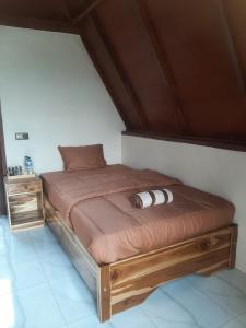ein Bett mit einem Holzrahmen in einem Zimmer in der Unterkunft Carasti Bungalows in Masbagik
